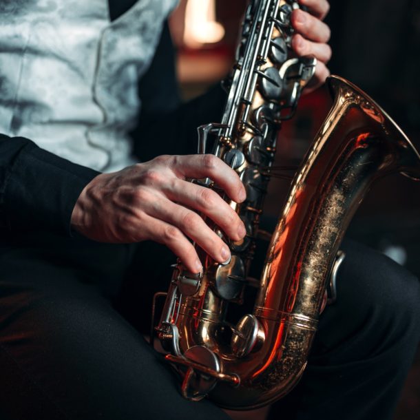 Jazz man hands holding saxophone closeup