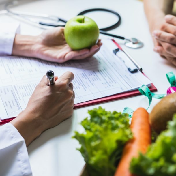 Nutritionist giving consultation to patient with healthy fruit and vegetable