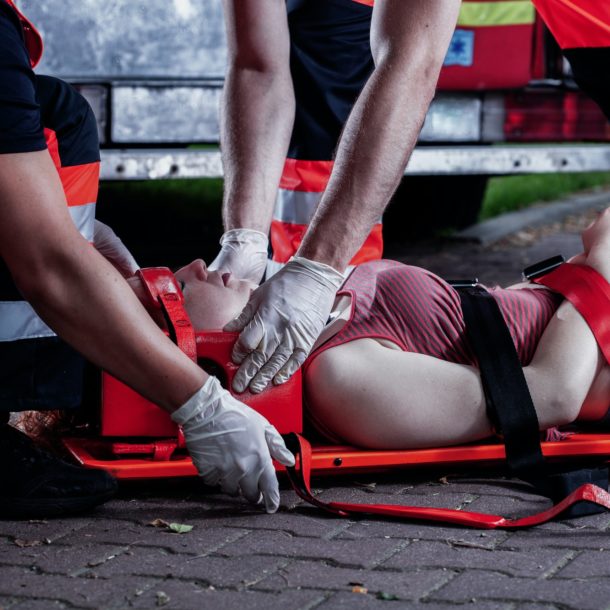 Professional medical rescuer bending over a car accident victim lying on a stretcher