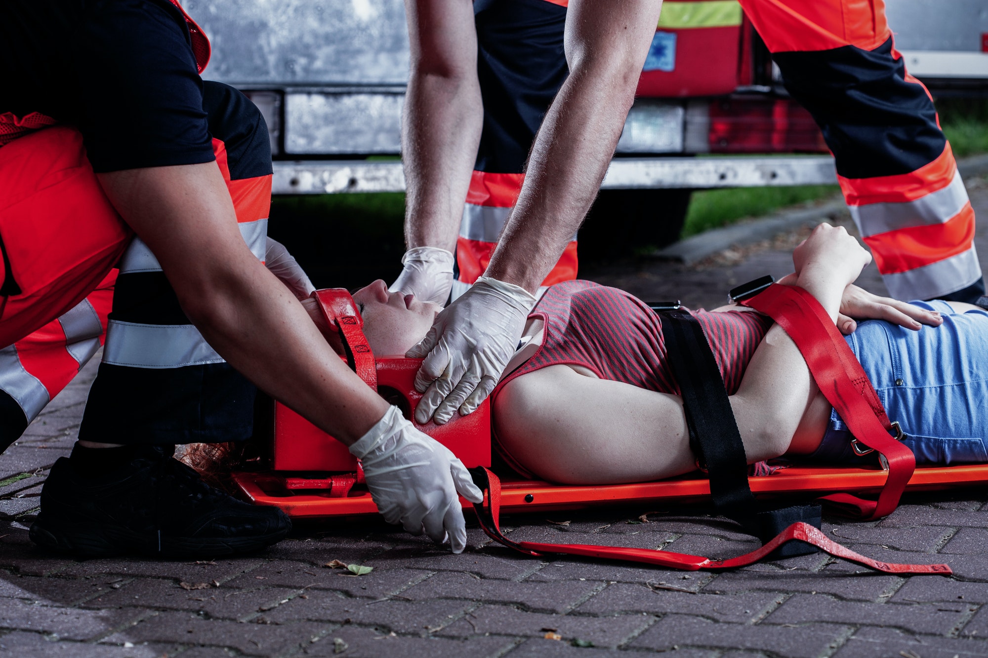 Professional medical rescuer bending over a car accident victim lying on a stretcher