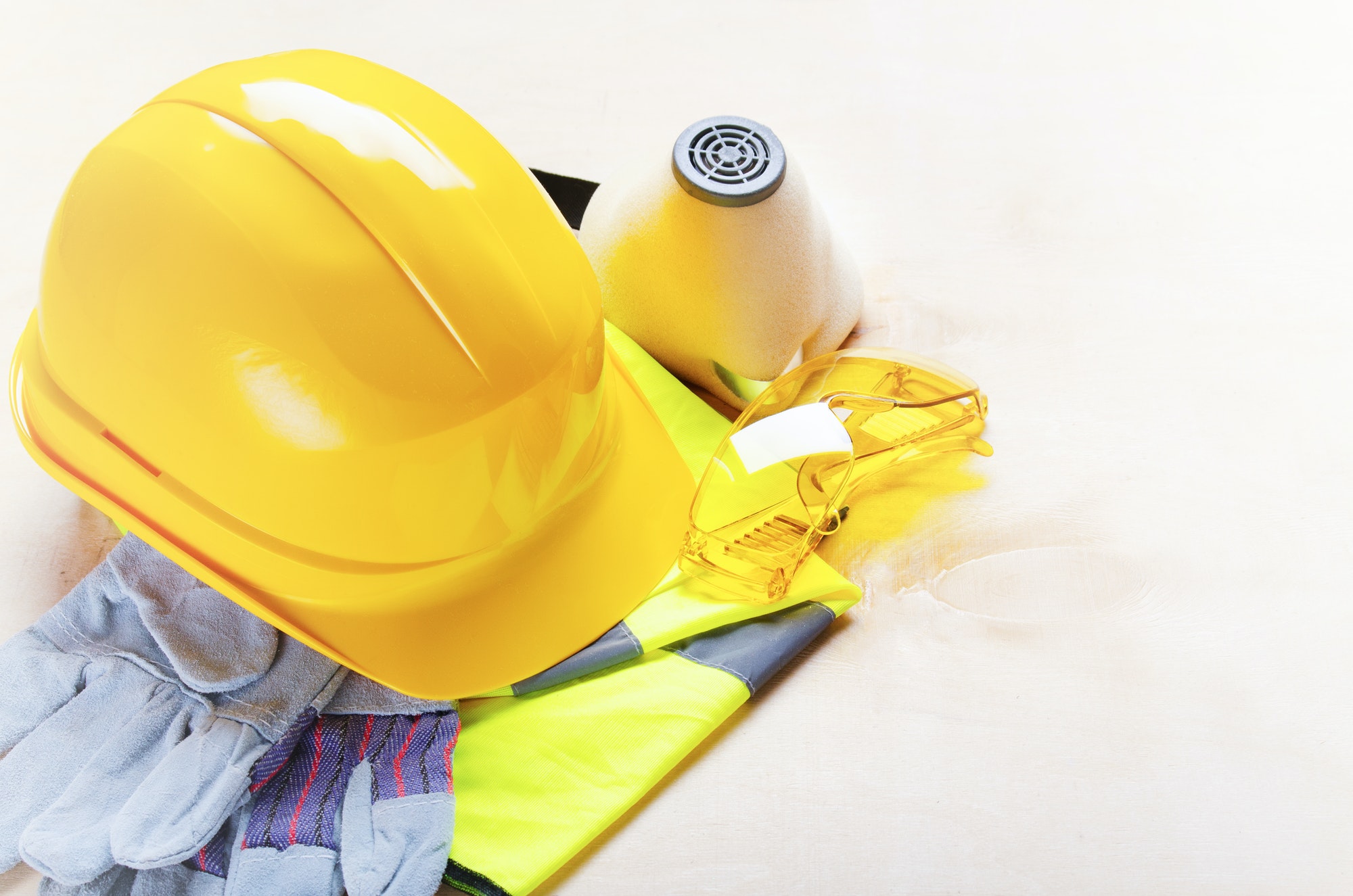 Yellow plastic hard hat, glasses, respirator, reflective vest and protective gloves