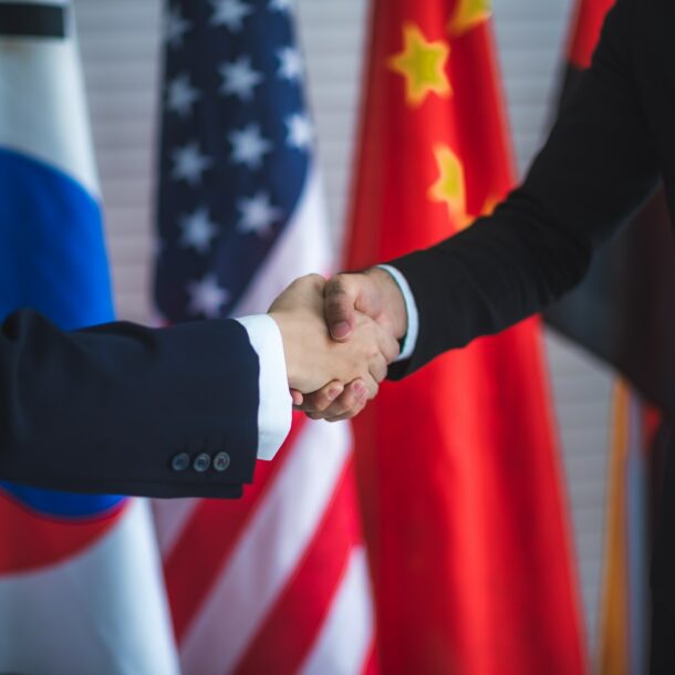 Business people shake hands, international flag background