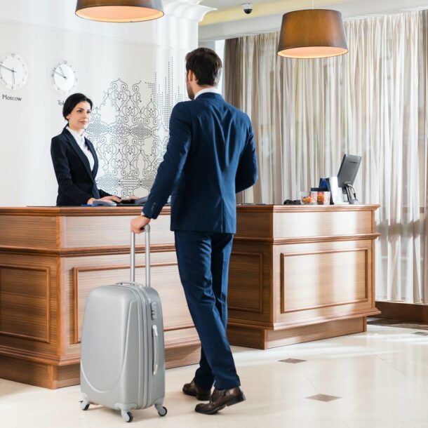 attractive receptionist looking at businessman with luggage