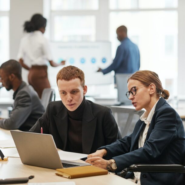 Two People using Laptop in Office