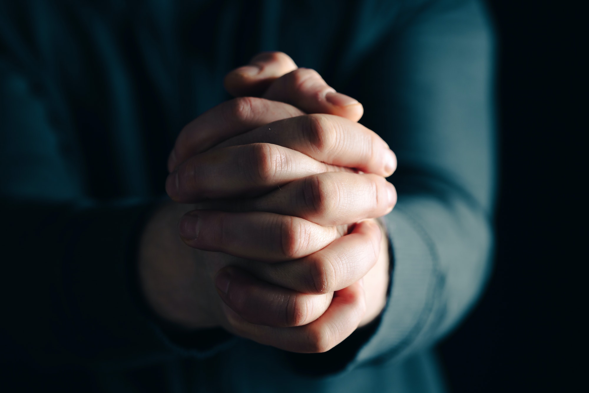 Man hands in praying position low key image