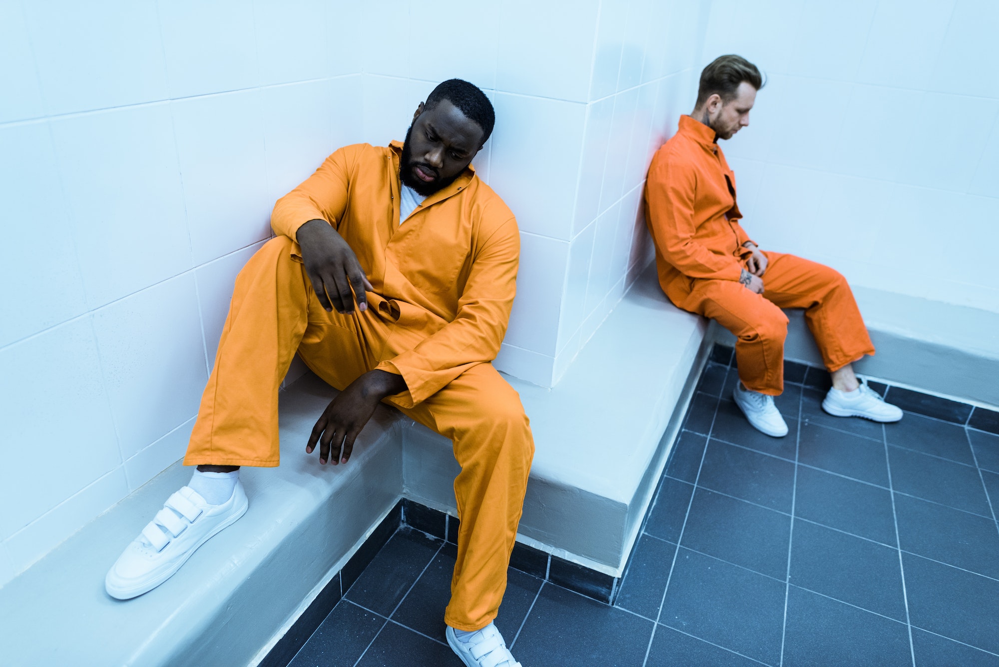 high angle view of multicultural prisoners sitting on benches in prison cell